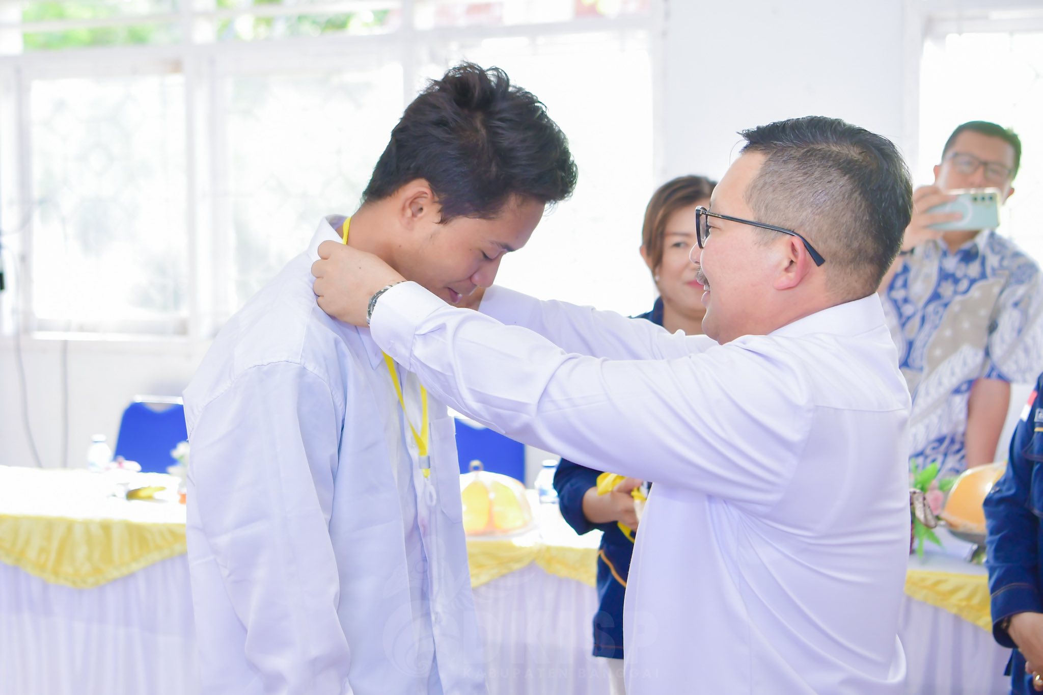 Bupati Banggai, H Amirudin saat menyematkan tanda peserta kepada salah satu pemuda yang akan mengikuti pelatihan pengelasan 6G di Batam, dalam acara pelepasan peserta pelatihan di Luwuk, Jum’at, 13 Juni 2025.